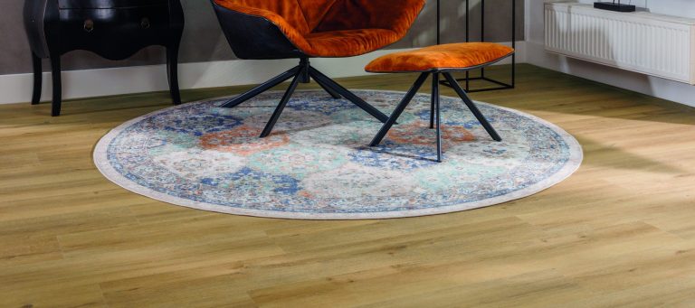 Eiken laminaatvloer in een woonkamer met een oranje fauteuil op een rond vloerkleed