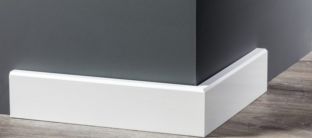 Witte moderne MDF plint langs een donkergrijze wand op een eiken vloer