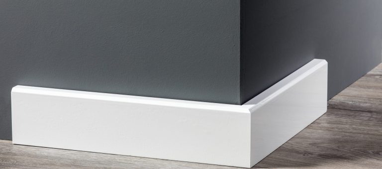 Witte moderne MDF plint langs een donkergrijze wand op een eiken vloer