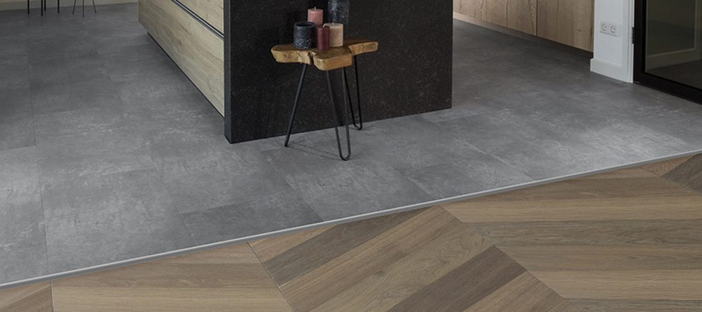 Vloerprofiel als overgang tussen een betonlook vloer en een visgraat houten vloer in een keuken