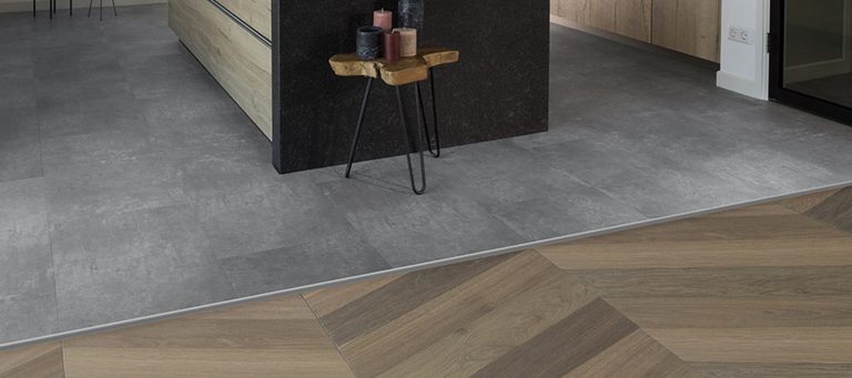 Vloerprofiel als overgang tussen een betonlook vloer en een visgraat houten vloer in een keuken