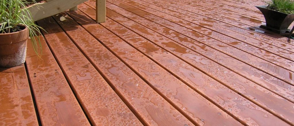 Houten vlonder met een verse olielaag waar de waterdruppels op blijven staan